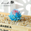 A vibrant blue and pink artificial succulent bonsai ball is displayed in a wooden box filled with small gravel.