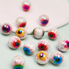 Un ensemble de dix perles de séparateur oculaires acryliques irisées de différentes couleurs éparpillées sur une surface blan