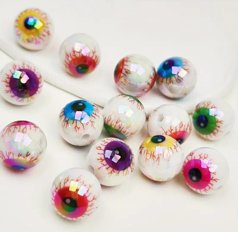Un ensemble de dix perles à lentilles oculaires en acrylique irisées avec des iris colorés et détaillés, éparpillés sur une s