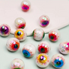 Un ensemble de dix perles de spacers oculaires en acrylique irisées avec des designs colorés et détaillés, éparpillées sur un