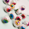 Un set de dix perles à séparateur d'yeux en acrylique iridescent avec des designs colorés et détaillés, éparpillées sur une s