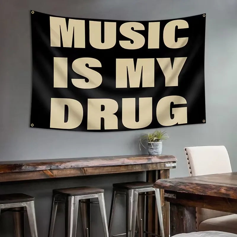 Black tapestry with white text that reads Music Is My Drug hanging above a wooden table.