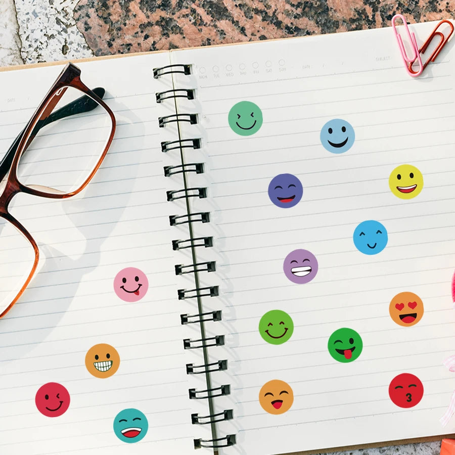 A spiral notebook page filled with colorful round expression stickers for packaging and organization.