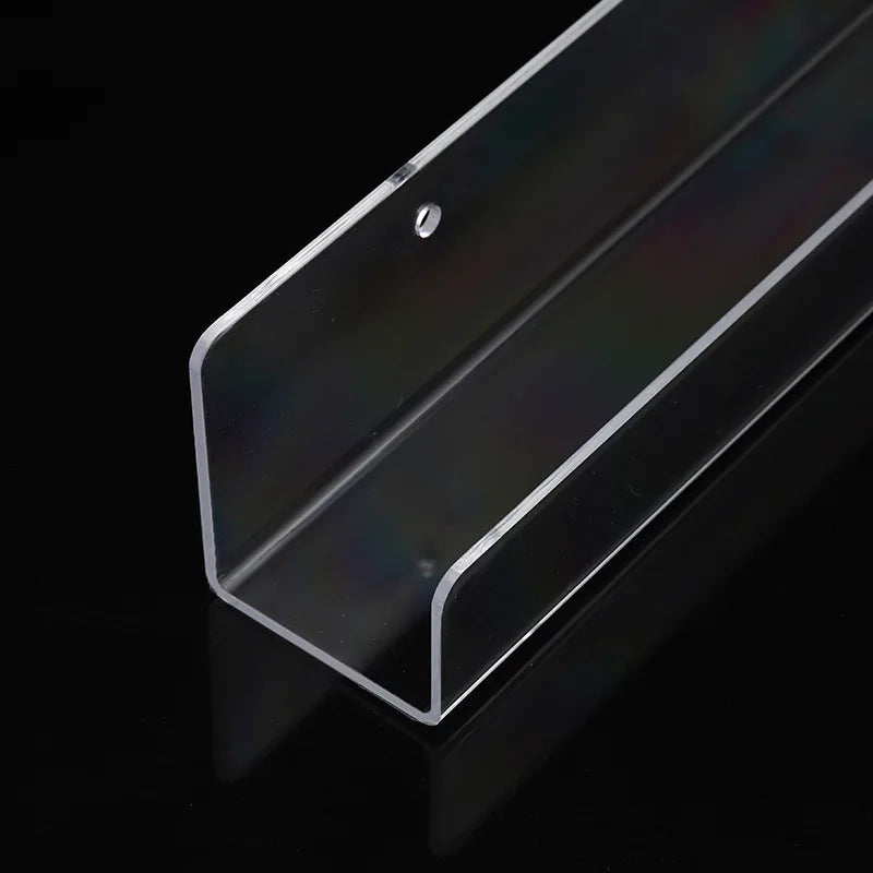 A clear acrylic floating shelf with a slanted top is shown against a black background.