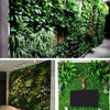A close-up of an artificial green plant wall panel featuring dense, realistic 3D foliage.