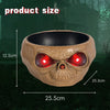 A terracotta skull bowl with glowing red eyes is shown against a dark, outdoor background.