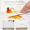 A hand wipes off an orange liquid stain from a white marble surface, demonstrating the waterproof and washable features of th