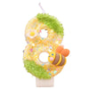 A yellow number eight candle decorated with green moss and small flowers, featuring a bee design.