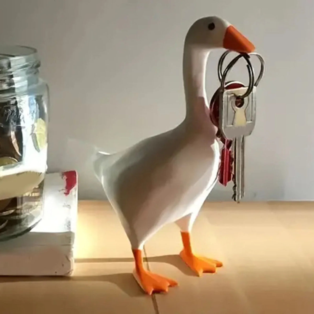 A white resin goose duck figure with orange legs standing next to a set of decorative keys.