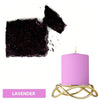 A purple candle in a gold wire holder next to a dark purple dye block.