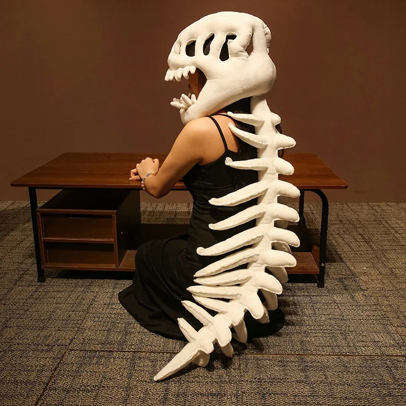 Une personne pose avec une peluche squelette de dinosaure blanc réaliste contre un mur marron et une table en bois.