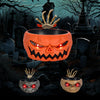 An orange carved pumpkin bowl with jagged teeth and eyes sits on a graveyard setting.