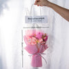 A pink handmade crochet yarn flower bouquet tied with a ribbon, displayed against a white sheer background.