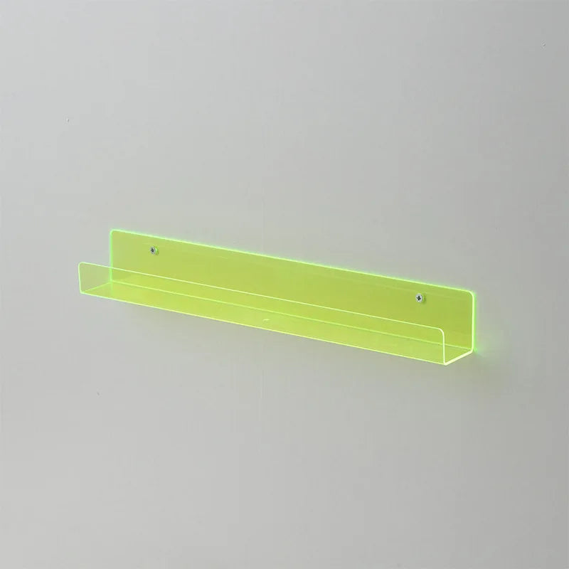 A long, narrow, translucent lime green acrylic floating shelf mounted on a white wall.