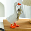 A white resin goose duck figurine with orange feet and a metal key holder attached.