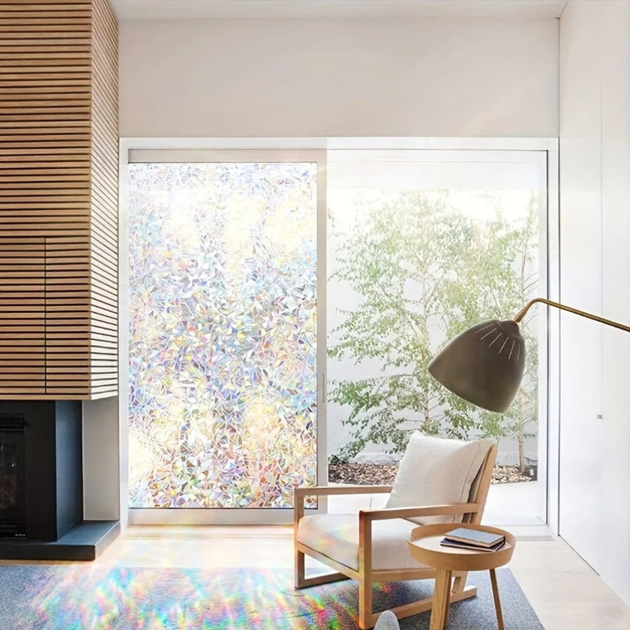 A modern interior featuring a window covered with rainbow holographic privacy film and a wooden chair.