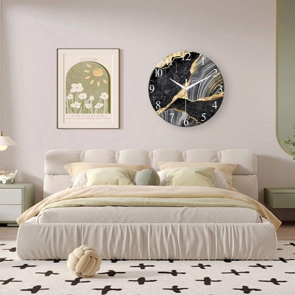 A modern marble textured glass wall clock with a white face and gold accents hangs above a beige upholstered bed.
