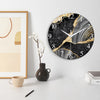 A round wall clock with a black and gold marble pattern on a white background, displayed on a light surface.
