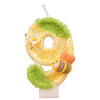 A yellow sequin birthday candle kit shaped like the number 8, decorated with green moss and a bee.