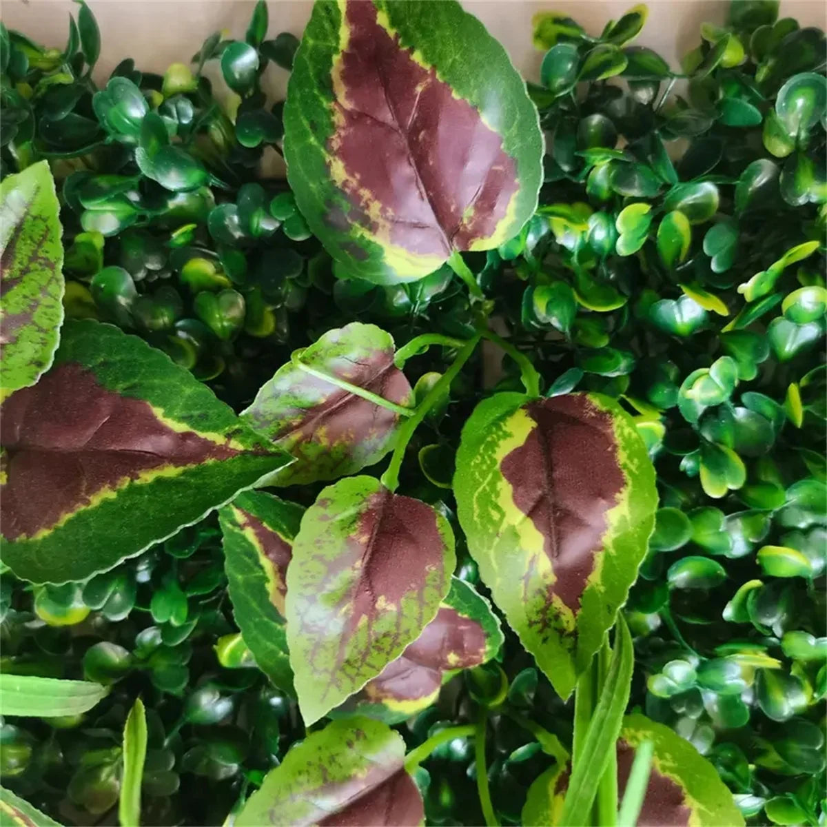 Artificial green plant wall panel featuring realistic 3D foliage with variegated green and brown leaves.