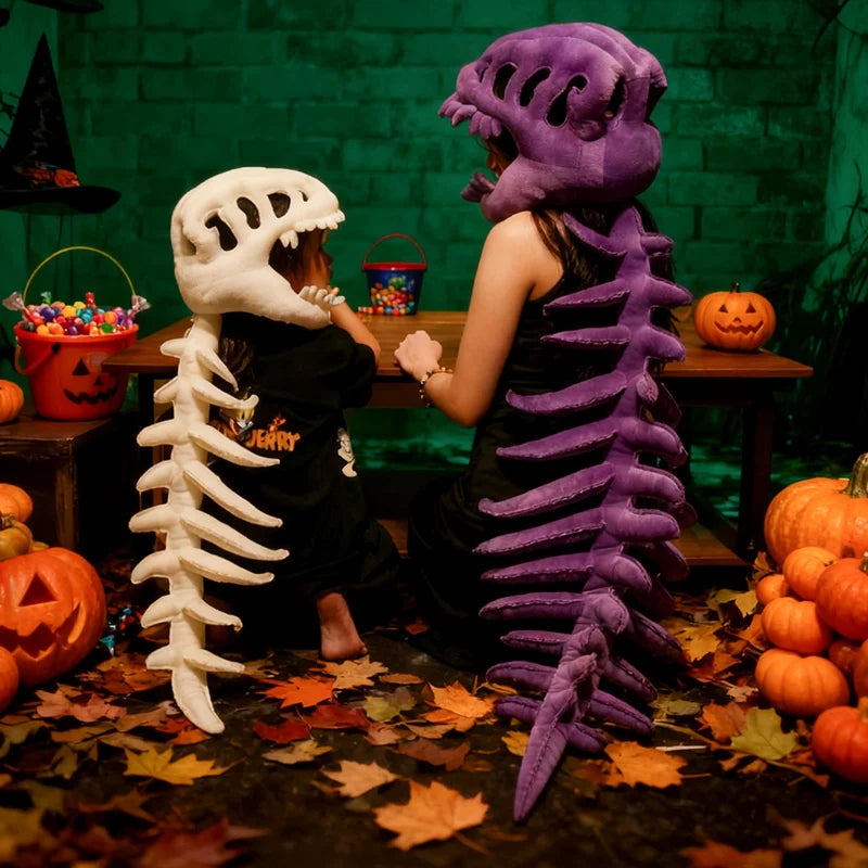 Un jouet en peluche violet, déguisé en squelette de dinosaure, se tient à côté d'un crâne blanc dans un décor d'Halloween.