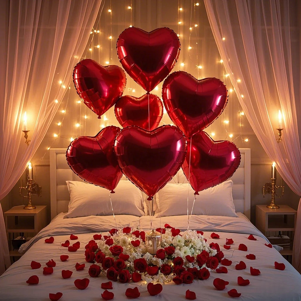 A bed decorated with red roses and heart-shaped foil balloons in a soft, warm light.