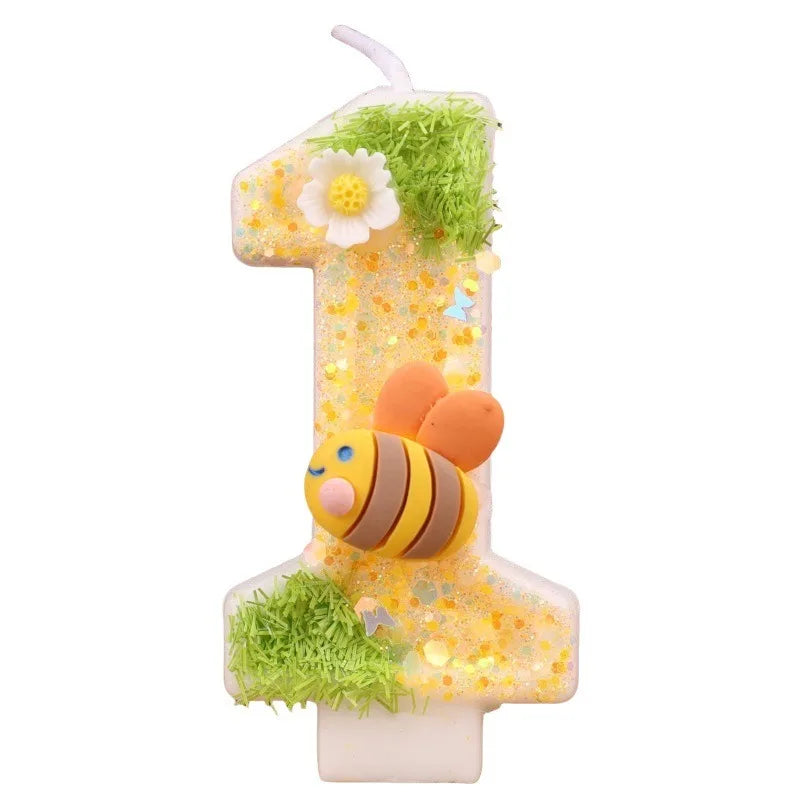 A golden number one candle decorated with green moss and a bee figure