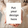 A person's hands are holding a blank white card with the text Put your design here on it.