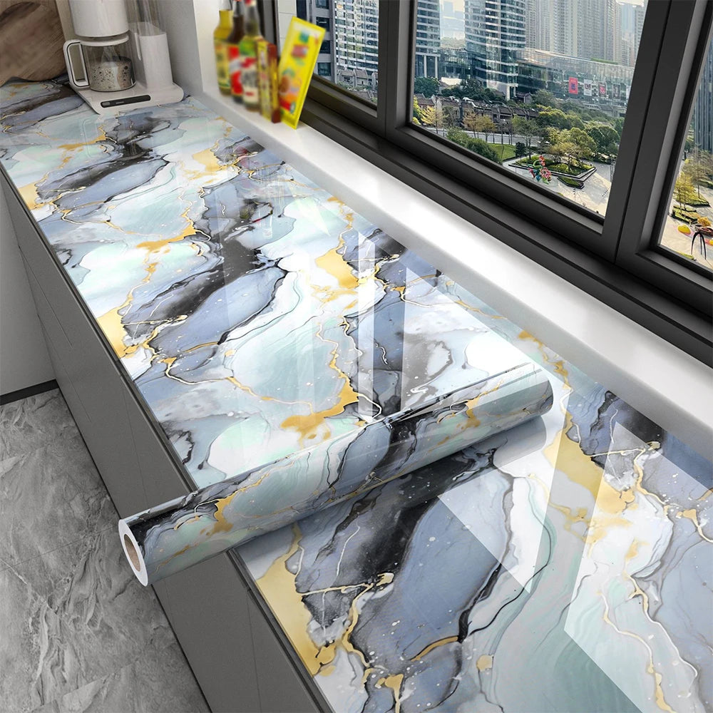 Marble pattern self-adhesive backsplash panel featuring gray, blue, and gold veining installed on a kitchen countertop.
