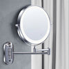 A round illuminated magnifying makeup mirror with a silver mounting bracket attached to a gray wall.