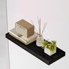 A rustic wood display featuring a rectangular box, some stacked books, and dried sticks on a black floating wall shelf.