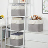 A set of four fabric storage cubes in gray and beige with light-colored handles displayed on a white metal shelf.