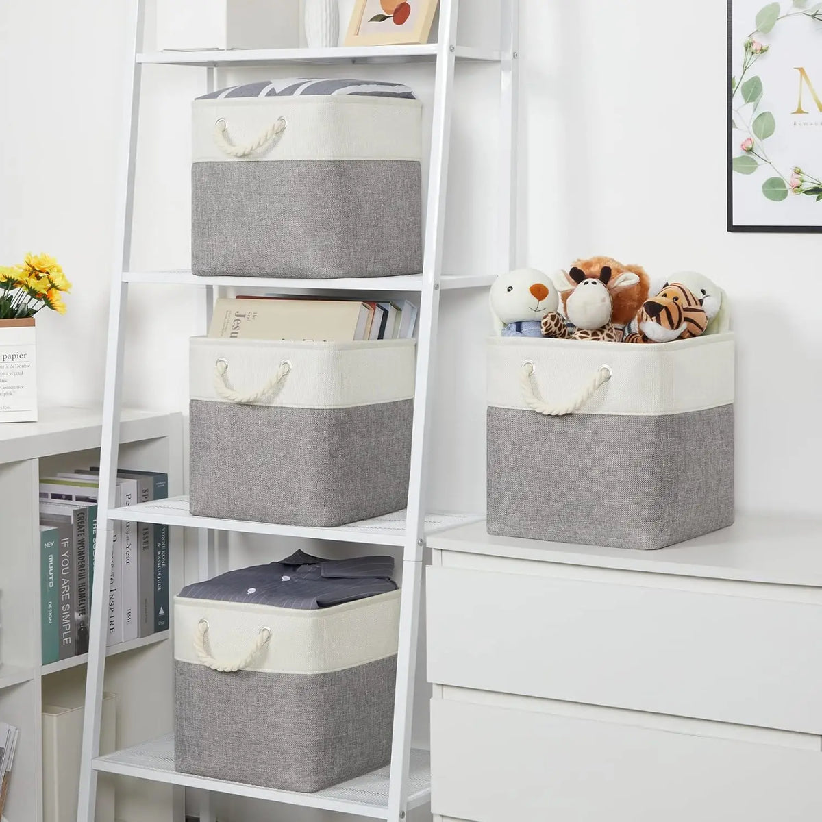 A set of four fabric storage cubes in gray and beige with light-colored handles displayed on a white metal shelf.