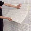 A person is applying self-adhesive 3D foam wall panels onto a white textured wall surface.