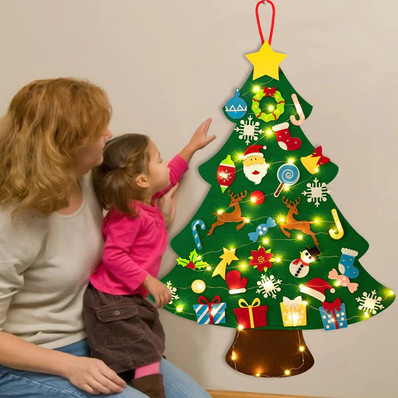 Una mujer y un niño decorando un árbol de Navidad verde con adornos de fieltro coloridos.