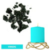 A teal blue candle in a gold wire holder next to black dye blocks.