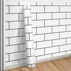 A roll of white and black grid peel-and-stick wallpaper mounted on a wall.