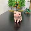 A small, pink pig figurine is displayed in front of a background featuring green trees with orange fruit.
