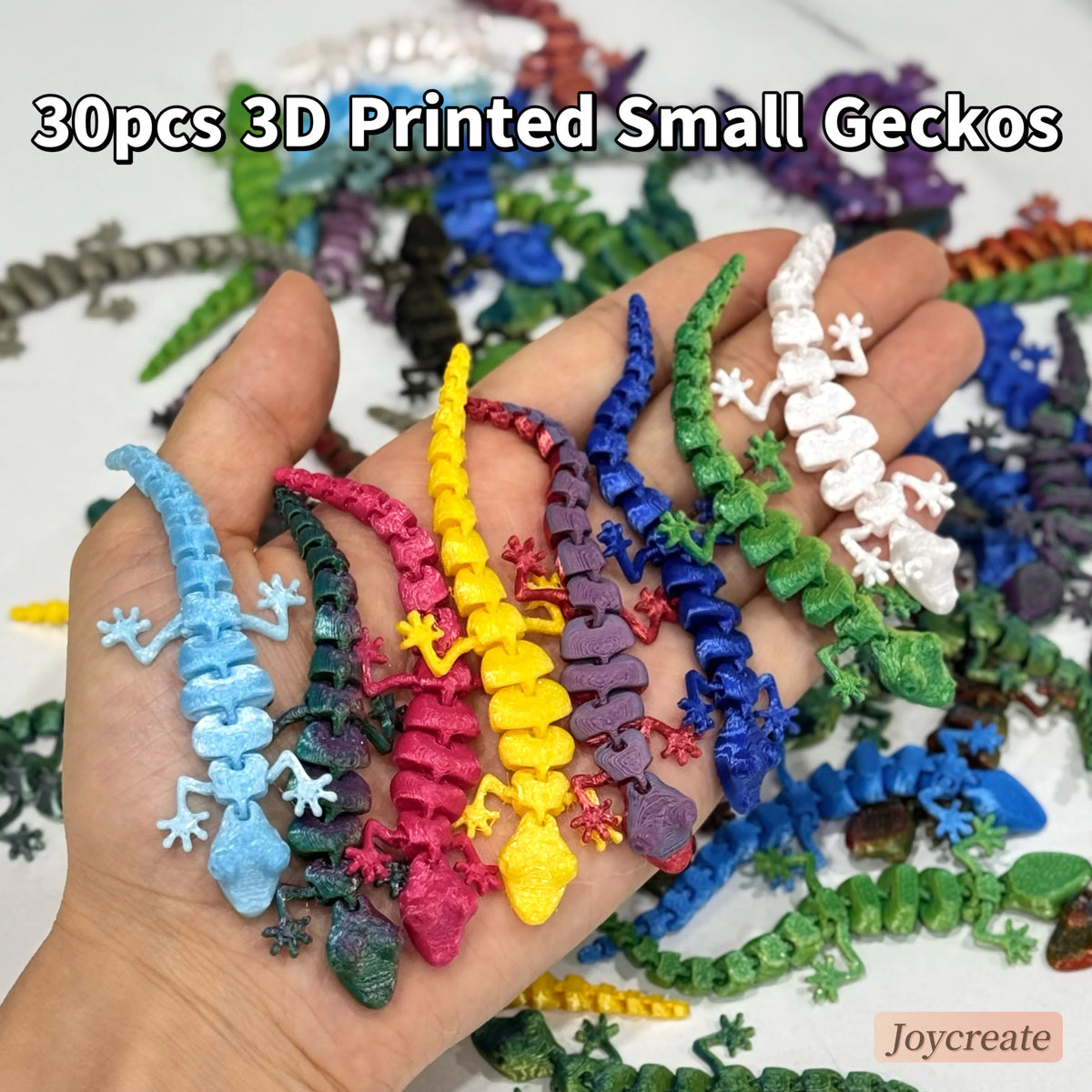 A hand holds a collection of 30 small 3D printed gecko figurines in various colors and shades.