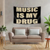 A black tapestry with the white text MUSIC IS MY DRUG hanging on a gray wall above a beige sofa.