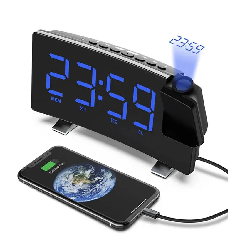 A black projection alarm clock with a large LED display showing 23:59 and an FM radio feature, next to a smartphone.