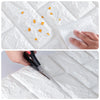 Close-up of self-adhesive 3D foam wall panels being applied to a white surface with small orange foam pieces scattered on the