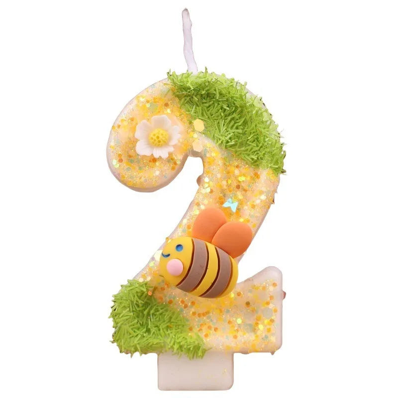 A golden number 2 candle decorated with green moss and yellow flowers, set in a birthday candle kit.