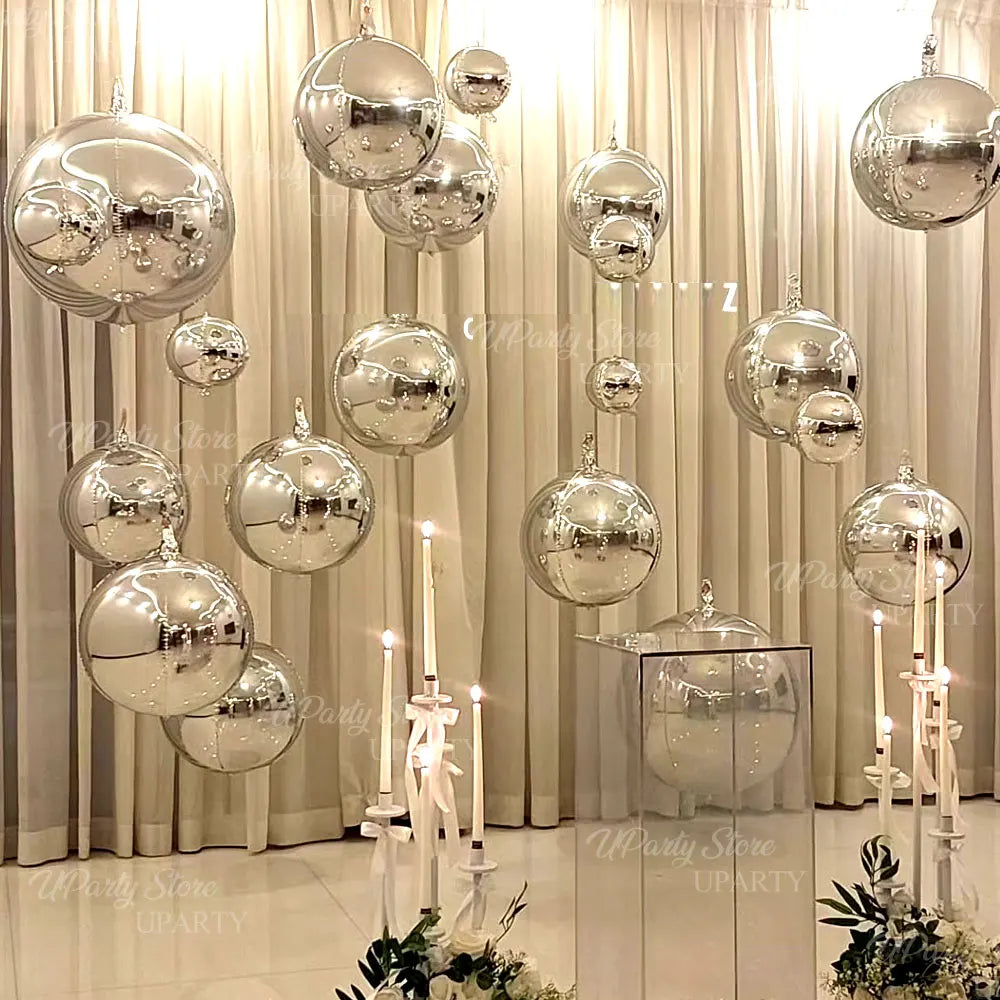 A display of metallic silver foil balloons hanging in front of sheer curtains.