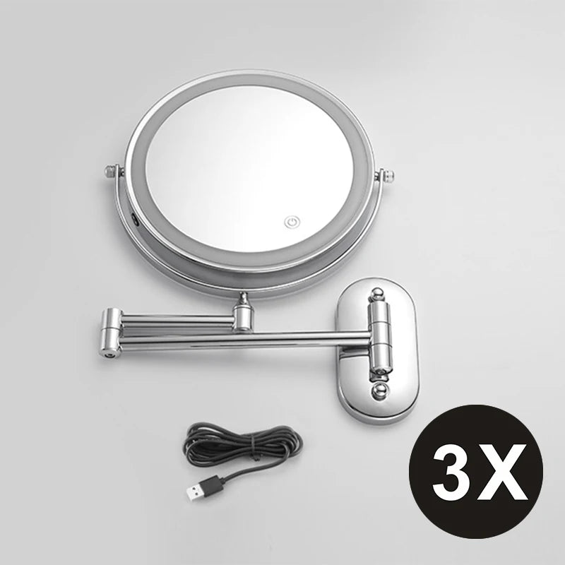 A round, silver-framed magnifying makeup mirror with a handle and USB charging cable.