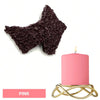 Pink candle in a gold wire holder next to a pile of dark pink candle dye blocks.