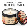 A jar of Pumpkin Chai doorstep candle with a lit wick and label showing seasonal imagery.