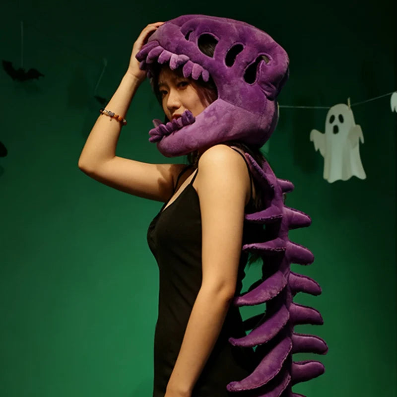 Une femme portant une peluche squelette de dinosaure violet sur un fond vert.