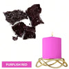 A pink candle in a gold wire holder next to dark purple and black dye blocks.