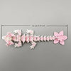 A delicate miniature figurine of a dragon made from pink cherry blossoms, measuring 15 cm long.